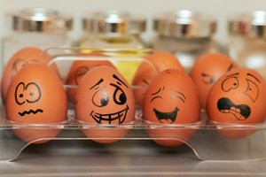 A clear plastic packet of eggs. Funny faces have been drawn on to the eggs