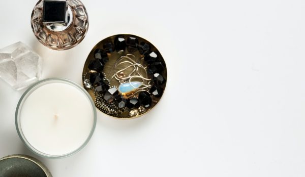 photo taken from above of a dish with jewelry in it, sitting next to perfume and candle